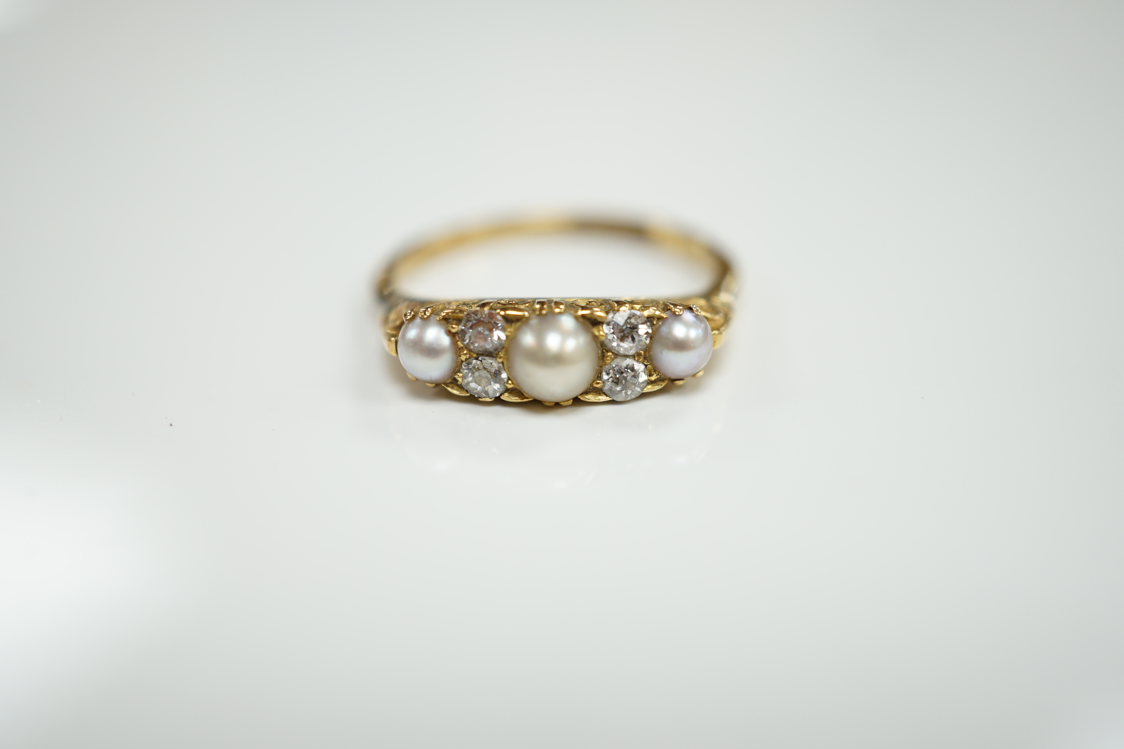 An early 20th century 18ct and plat, three stone split pearl and four stone diamond set half hoop ring, size P, gross weight 3.2 grams.